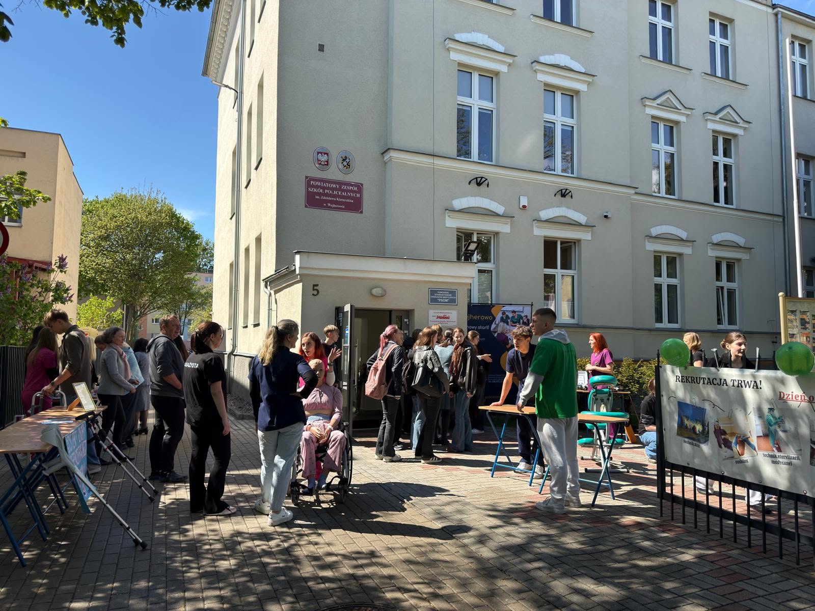 Zdjęcie grupy ludzi przed wejściem do szkoły.
