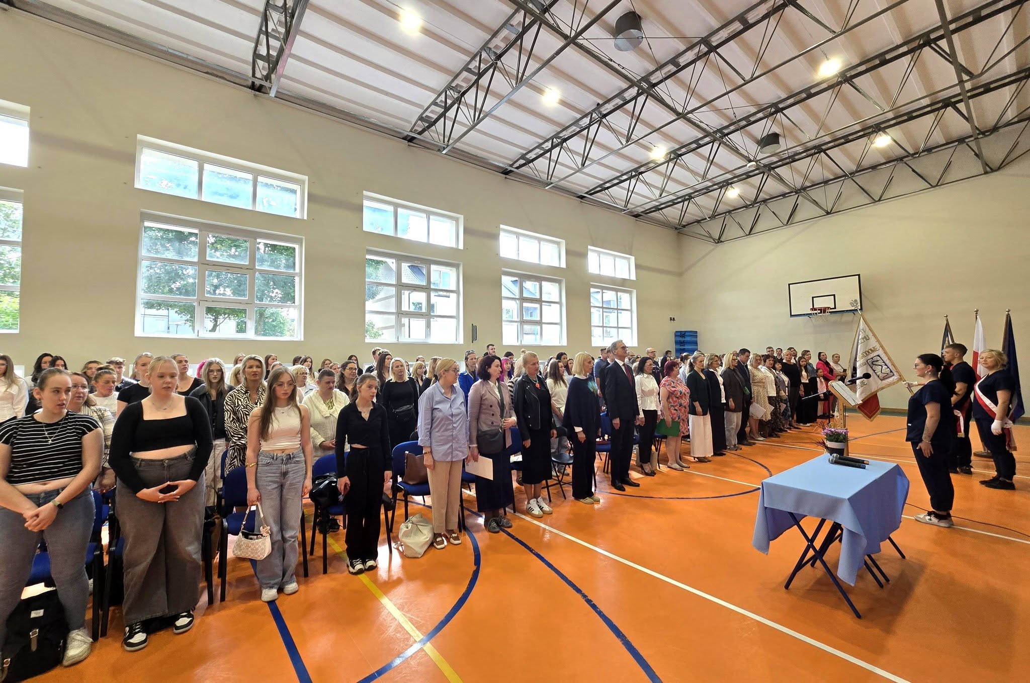 Zdjęcie grupowe nauczycieli i dyrekcji podczas rozpoczęcia na Hali Sportowej.